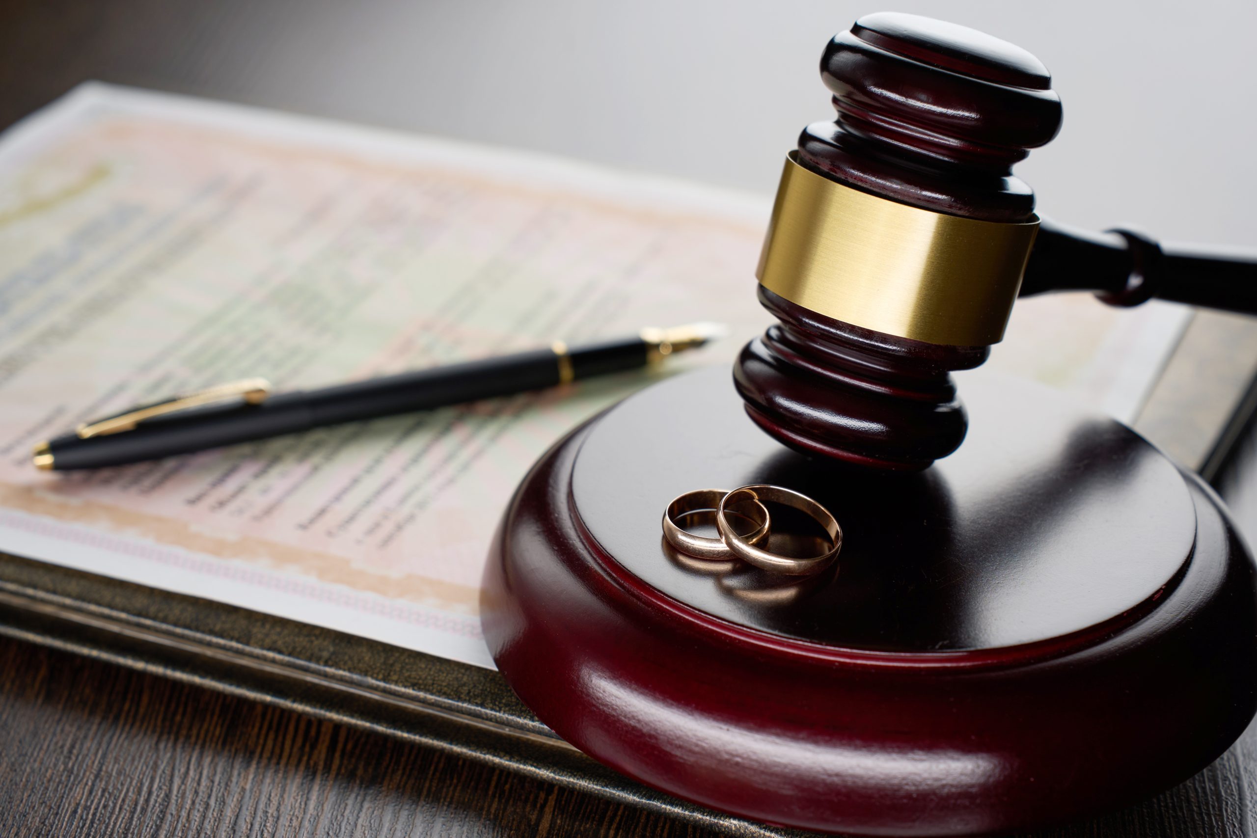 Divorce decree or marriage contract. Judge gavel with wedding rings and divorce decree. Marital agreement, legalities of divorce documents. The article this image is on talks about How Marriage, Divorce, or Separation Can Affect Immigration Status