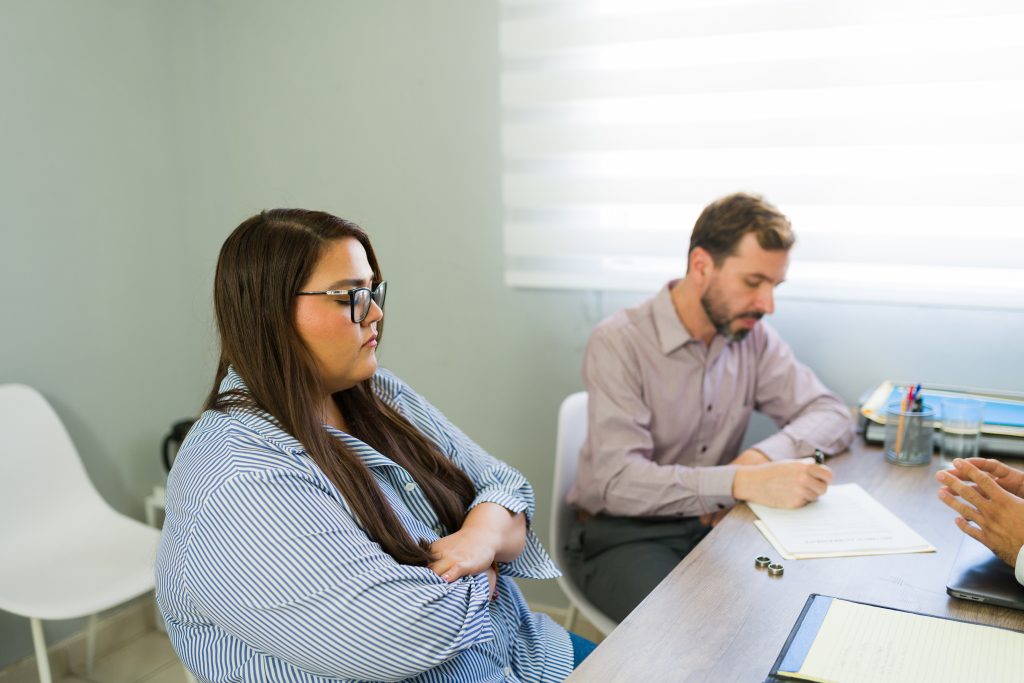 Upset woman and man signing divorce papers in a lawyer's office, ending their marriage and a difficult relationship
