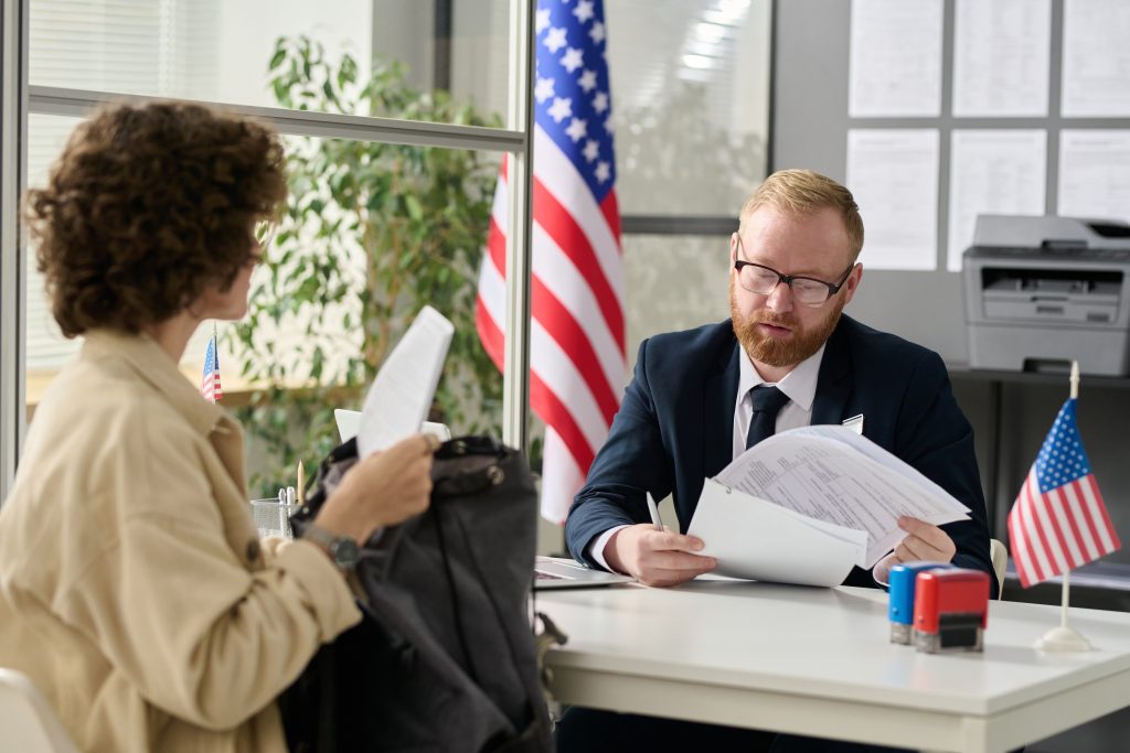 Portrait of male immigration attorney revising documents of young woman applying for green card.