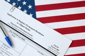 Adjustment of Status application and a pen on top of the US flag